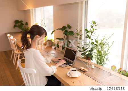 カフェでノートパソコンを使う女性の写真素材