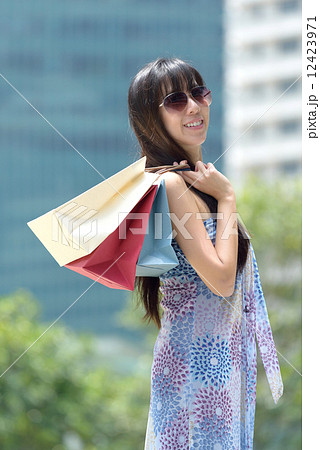 Young chinese woman shopping with shades and shopping bags standing outside of mall along promenade Young chinese woman shopping with shades and shopping bags standing outside of mall along promenade 12423971