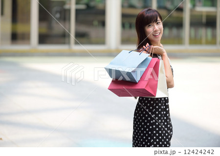 Young chinese woman shopping with shopping bags standing outside of mall along promenade 12424242