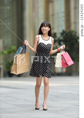 Young chinese woman shopping with shopping bags standing outside of mall along promenade Young chinese woman shopping with shopping bags standing outside of mall along promenade 12424305