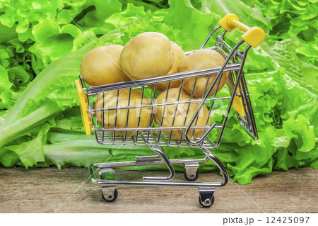 Shopping cart with potatoes on a lettuce background 12425097