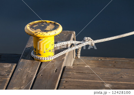 Yellow mooring bollard with nautical rope on pier Yellow mooring bollard with nautical rope on pier 12428100
