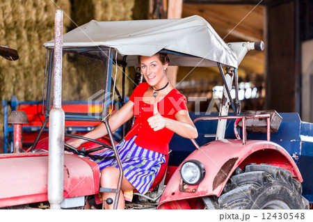 Bavarian woman with Dirndl dress driving tractor 12430548