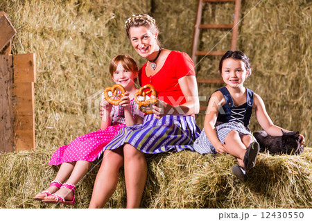 Bavarian family sitting on hayloft with pretzels 12430550