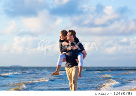 man carrying woman piggyback at beach man carrying woman piggyback at beach 12430793