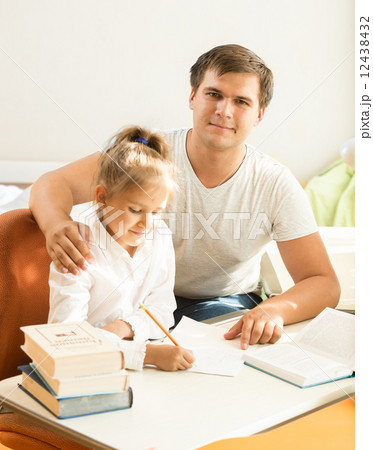 handsome man helping daughter with homework handsome man helping daughter with homework 12438432