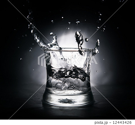 ice cube splashing into a glass full of water 12443426