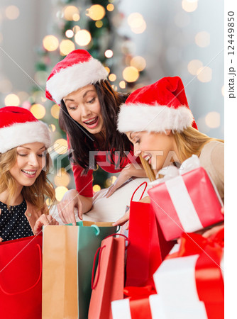 smiling young women in santa hats with gifts smiling young women in santa hats with gifts 12449850