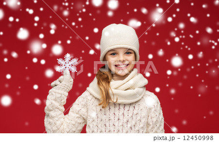 smiling girl in winter clothes with big snowflake 12450998