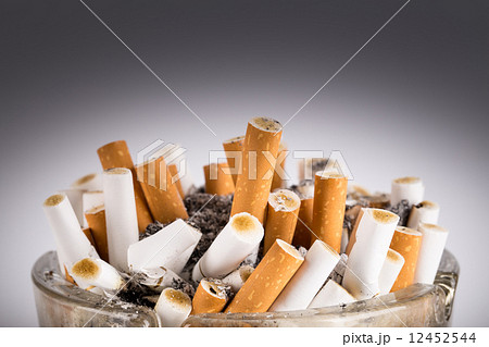 A dirty ashtray with cigarette ash and butts 12452544