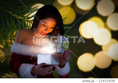Composite image of sexy santa girl opening gift 12453436