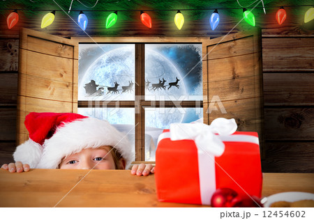 Composite image of festive boy peeking over table 12454602