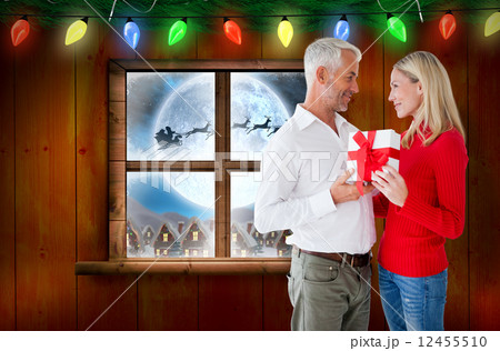 Composite image of loving couple with gift Composite image of loving couple with gift 12455510