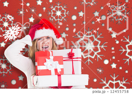 Composite image of festive blonde holding pile of gifts 12455758