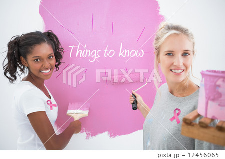 Composite image of smiling housemates painting wall pink Composite image of smiling housemates painting wall pink 12456065