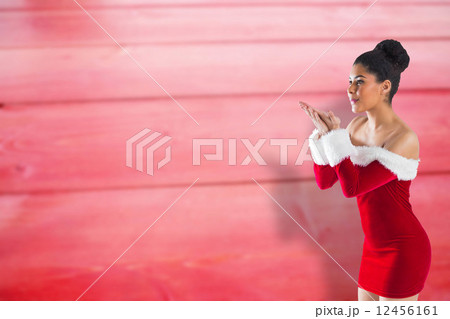 Composite image of pretty santa girl blowing over her hands Composite image of pretty santa girl blowing over her hands 12456161