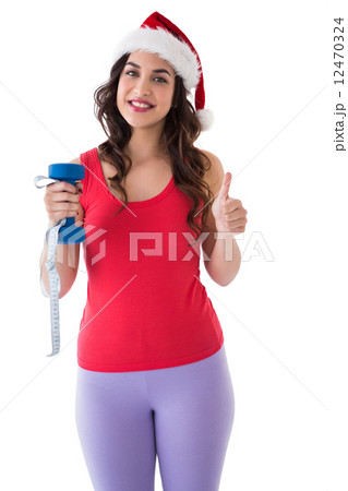 Festive fit brunette holding measuring tape and dumbbell 12470324