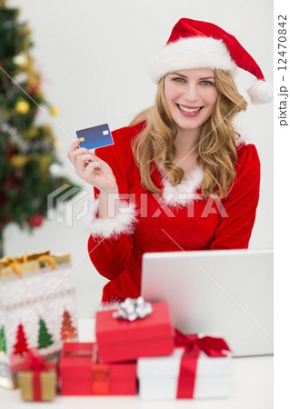 Blonde shopping online with laptop while smiling at camera 12470842