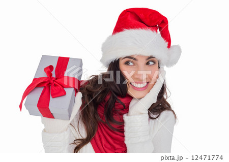 Surprised brunette in santa hat holding gift Surprised brunette in santa hat holding gift 12471774