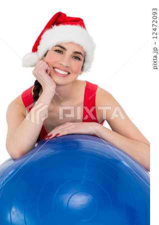 Festive fit brunette leaning on exercise ball 12472093