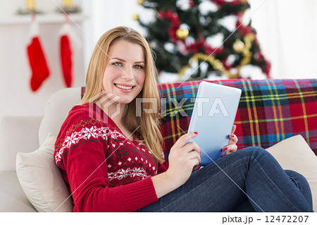 Pretty girl lying on sofa using her tablet smiling at camera Pretty girl lying on sofa using her tablet smiling at camera 12472207