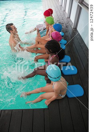 Cute swimming class in pool with coach 12472439