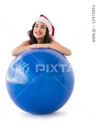 Festive fit brunette leaning on exercise ball 12472651