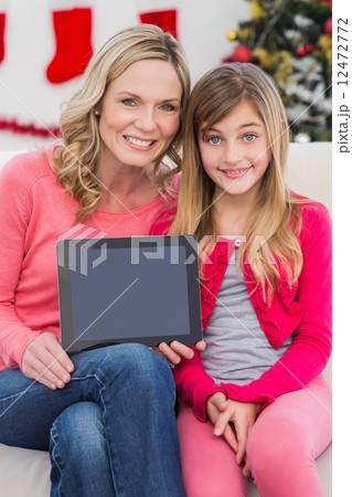 Festive mother and daughter showing tablet screen 12472772