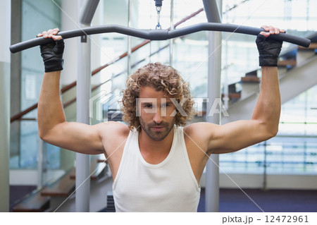 Handsome man exercising on a lat machine in gym 12472961