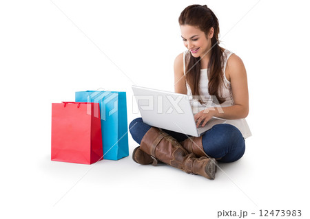 Smiling brunette sitting and using her laptop Smiling brunette sitting and using her laptop 12473983