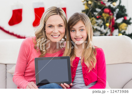 Festive mother and daughter showing tablet screen Festive mother and daughter showing tablet screen 12473986