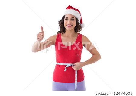Festive fit brunette measuring her waist 12474009