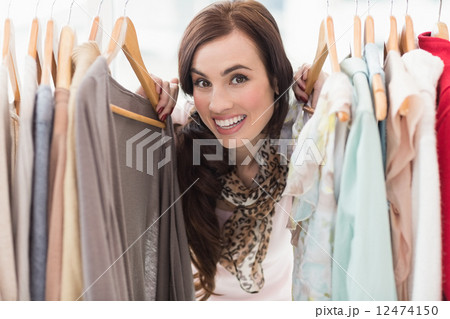 Pretty brunette smiling at camera by clothes rail Pretty brunette smiling at camera by clothes rail 12474150
