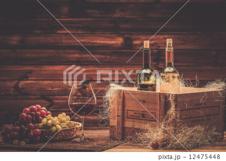 Bottles of red and white wine, glass and grape on a wooden interior 12475448