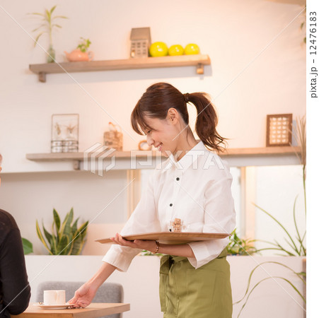 コーヒーを運ぶカフェ店員の写真素材