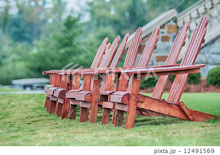 Two wooden adirondack chairs on lush green lawn Two wooden adirondack chairs on lush green lawn 12491569