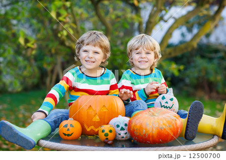 Two little friends boys making jack-o-lantern for halloween in a 12500700