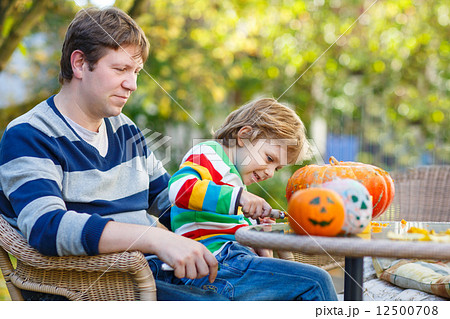 Young dad and his little son making jack-o-lantern for halloween 12500708