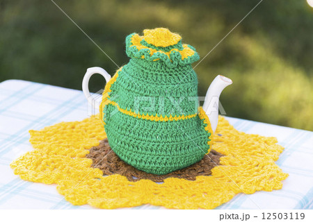 Knitted doily on the teapot on a natural background. 12503119
