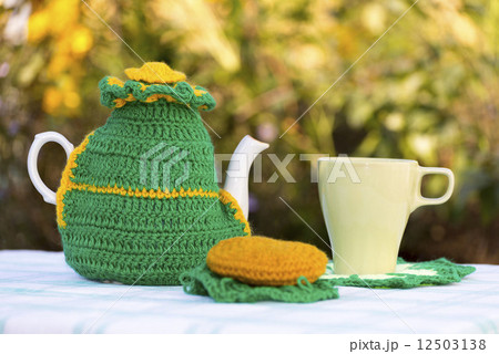 Knitted doily on the teapot on a natural background. 12503138