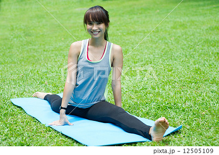 Young and beautiful asian lady doing yoga on a mat in the garden Young and beautiful asian lady doing yoga on a mat in the garden 12505109