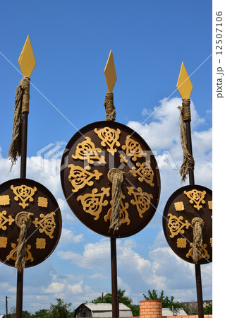 Oriental shields with gilded decoration hanging on decorative spears 12507106