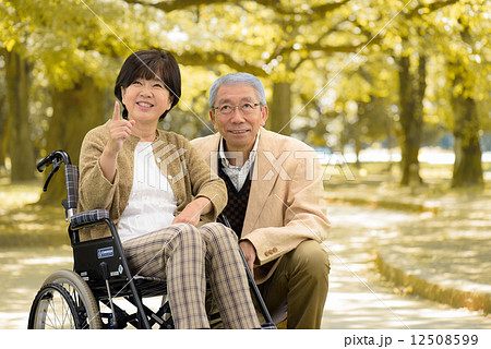 秋の公園で車いすで散策するシニア夫婦 秋の公園で車いすで散策するシニア夫婦 12508599