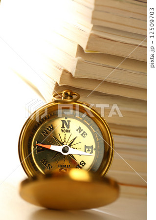 Stack of magazines and golden compass 12509703