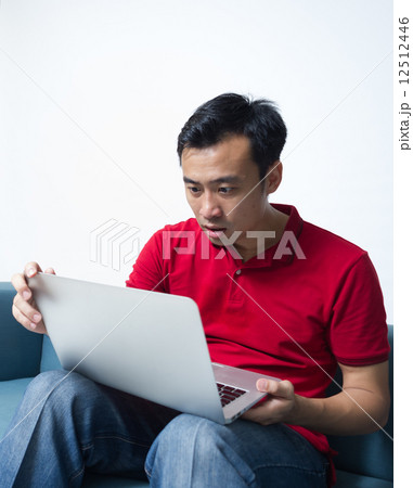 A middle-age Asian adult was shocked by the news he read on his laptop 12512446