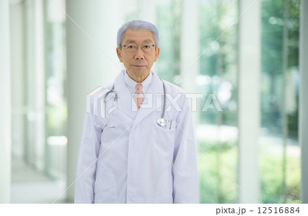 大病院のエントランスに立っているロマンスグレーの医師 12516884