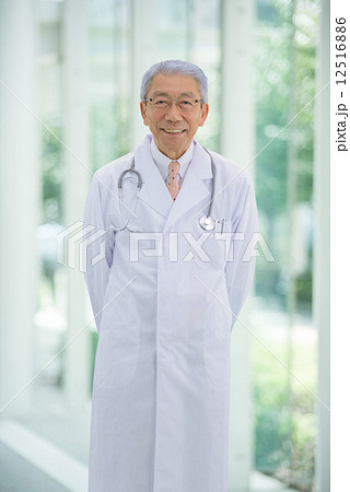 大病院のエントランスに立っているロマンスグレーの医師 12516886