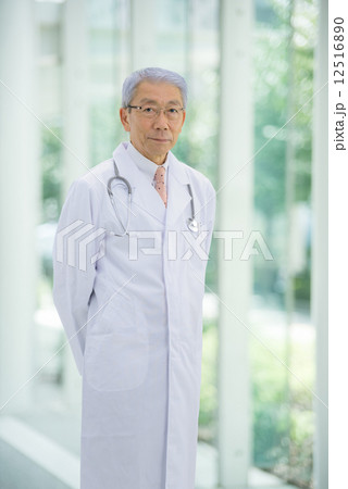 大病院のエントランスに立っているロマンスグレーの医師 12516890