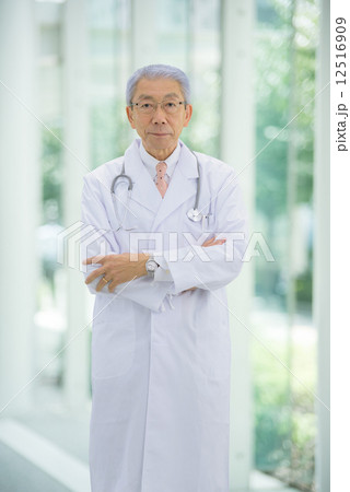 大病院のエントランスに腕組みをしながら立っているロマンスグレーの医師 12516909