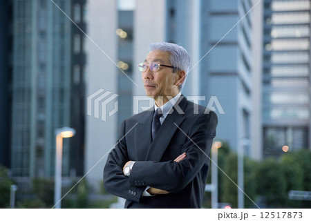 夕暮れの高層ビル街に腕組みをして立つエグゼクティブ 夕暮れの高層ビル街に腕組みをして立つエグゼクティブ 12517873